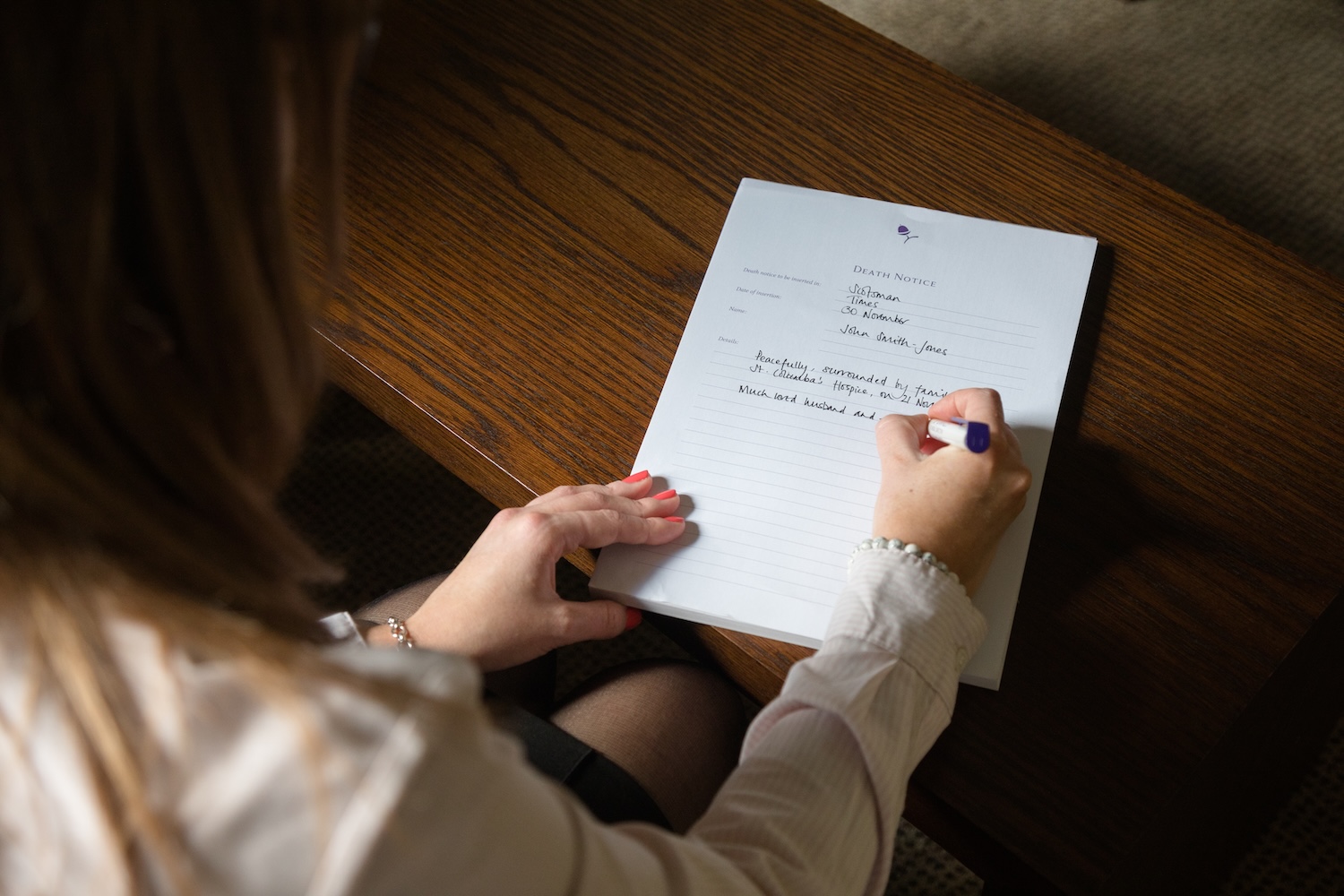 A person writing a death notice