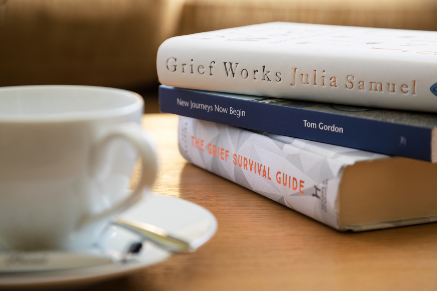 A stack of books about grief beside a tea cup.