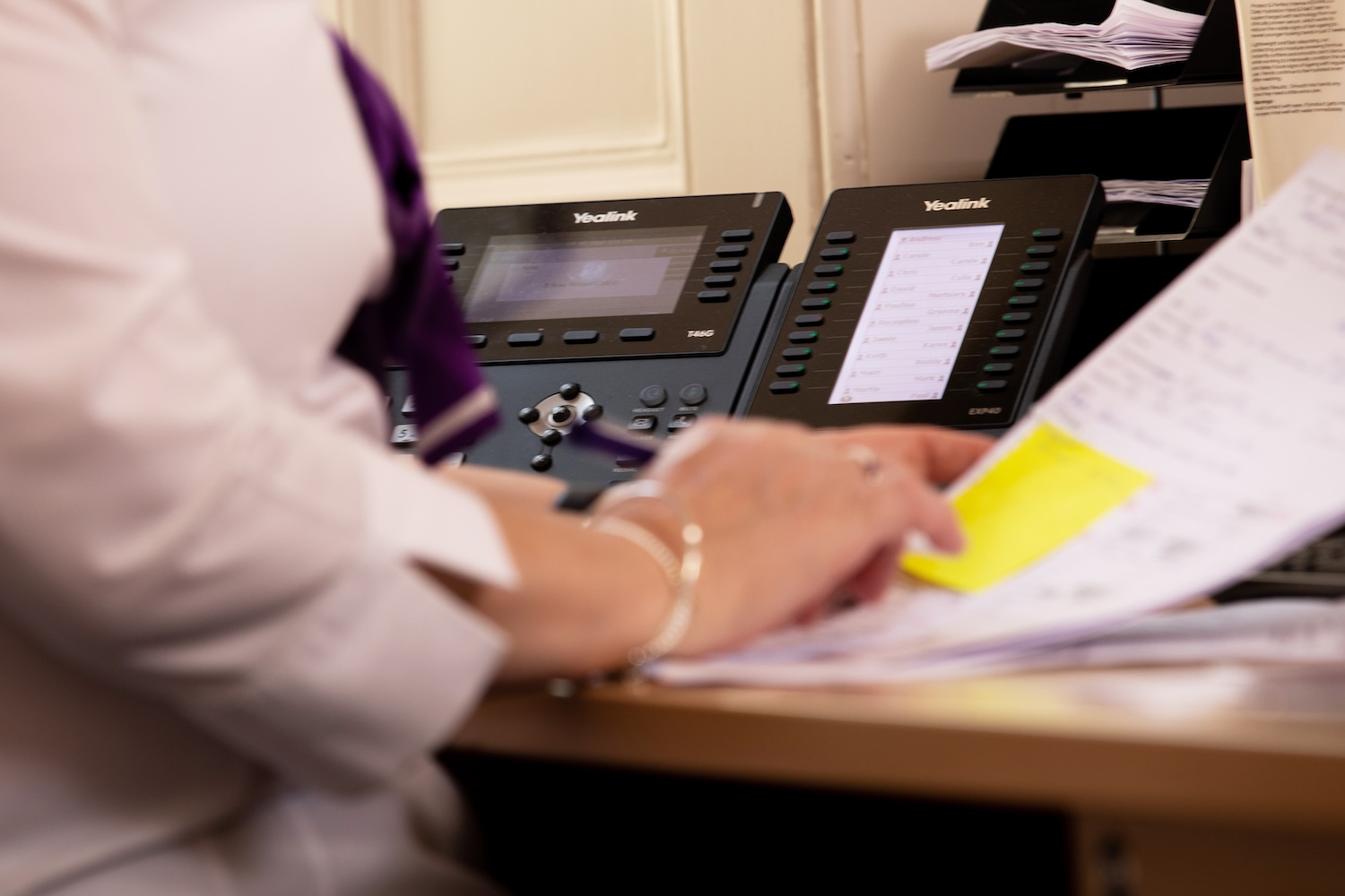 A person working at a desk with papers and a phone