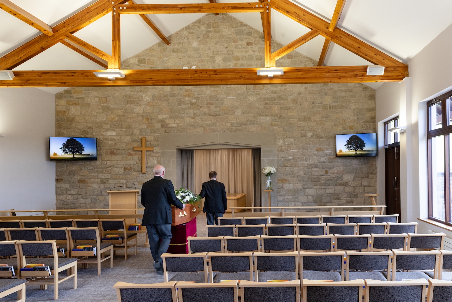Two funeral directors escorting a coffin to the cremation area