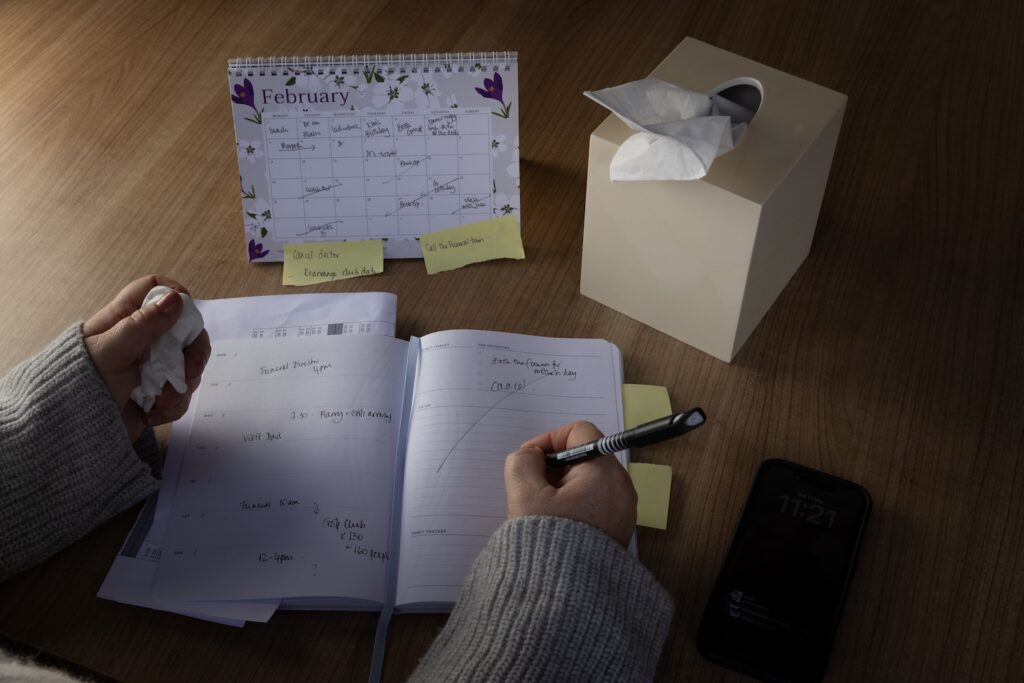 A grieving person writes in their diary, planning a funeral