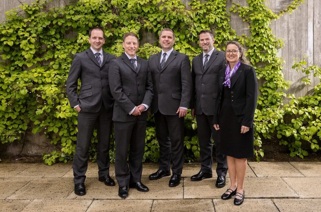 Five members of the William Purves staff, standing in front of a wall with leaves