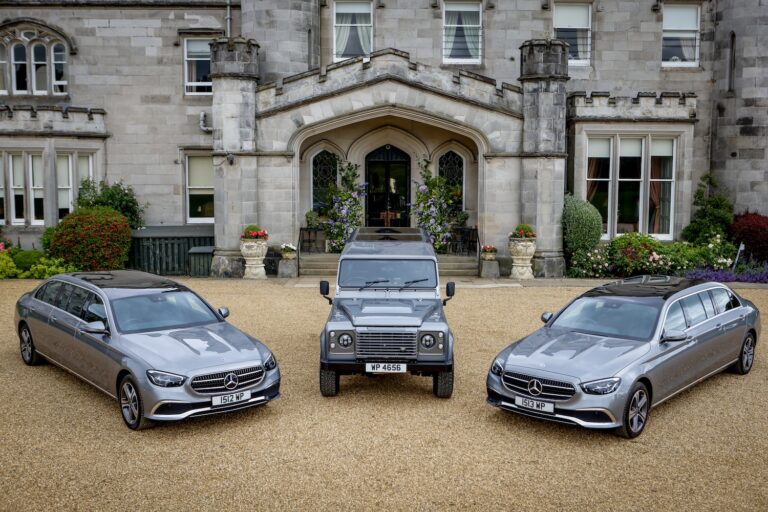 Three cars parked outside of a manor house